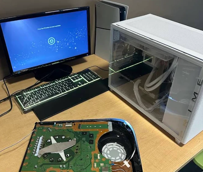 PlayStation 5 disassembled motherboard beside custom liquid-cooled PC rig